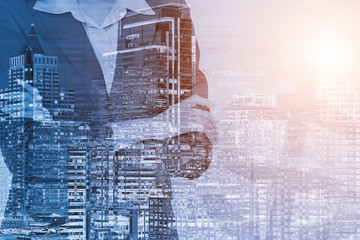 Double exposure of businesswoman arms crossed and urban building