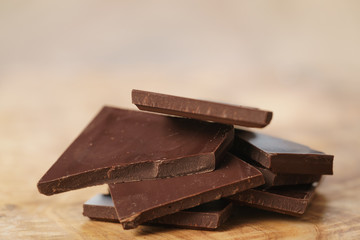 stacked pieces of chocolate bar on wooden table, shallow focus