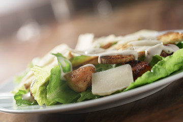 angle shot of caesar salad with chicken on old wooden table, shallow focus