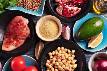 Ingredients of middle eastern cuisine - chickpeas, lentils, couscous, pomegranate, red onion, tomato, avocado,  chicken breast, paprika, parsley, olive oil and garlic.