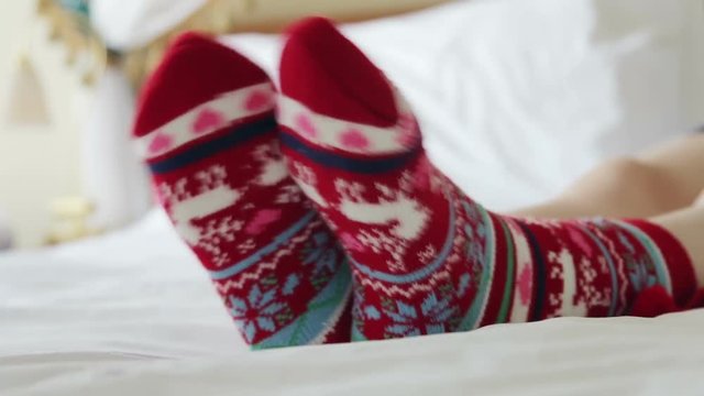Female legs in Christmas socks in bed