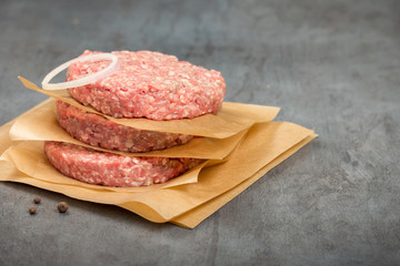 Raw ground beef meat cutlets on a stone surface