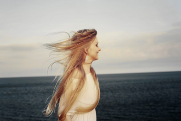 Obraz premium Beautiful blond woman in white dress enjoying the sea wind. Freedom to travel, enjoy nature, happiness
