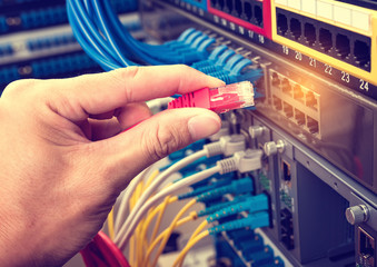 hand with network cables connected to servers in a datacenter