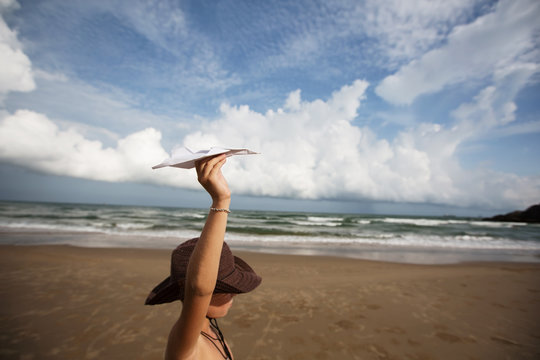 Little boy on ocean beach with paper plane