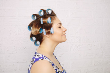 Naklejka premium Happy smiling casual Woman in hair salon with big hair curlers on head