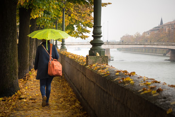 Donna con ombrella che cammina in una giornata autunnale