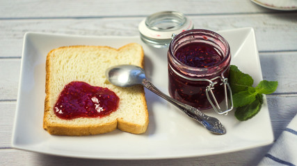 raspberry jam in a jar with toast. selective focus