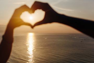 Love shape hand silhouette in sunset or sunrise on ocean beach