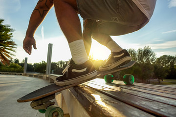 Silhouette of young man perfoming with skateboard up wood bench