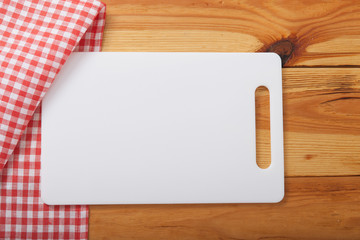 Cutting board over towel on wooden kitchen table. Top view