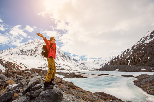 Happy hiking man in high snow mountains near mountain ice lake