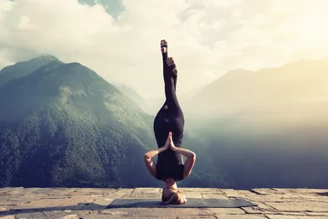Foto op Canvas Jonge vrouw doet complexe Yoga oefening headstand met Namaste asana. Geweldig yogalandschap in prachtige bergen © Annatamila