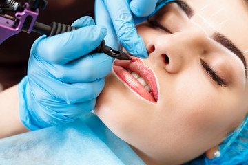 Naklejka premium Cosmetologist making permanent makeup on woman's face