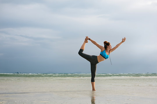 Yoga woman on the beautiful beach. Standing yoga asana
