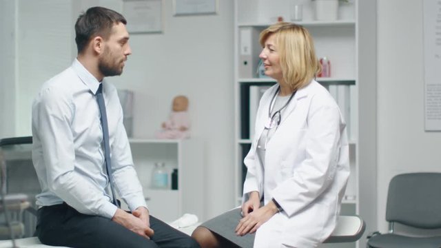 Mid Adult Female Doctor Consults Young Man About His Back Pain.  Shot on RED Cinema Camera in 4K (UHD).