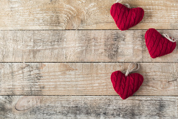 three knitted red  hearts on wooden rustic background