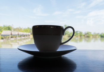 Silhouette Of a cup of coffee and breathtaking views of the fishing park from coffee cafe.