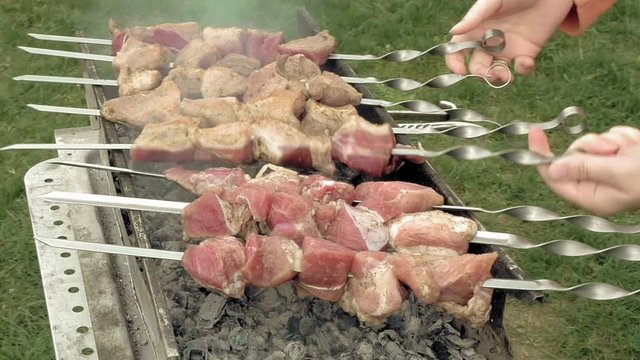 Girl cooks barbeque skewers with meat on hot coal ember brazier Outdoors picnic concept.