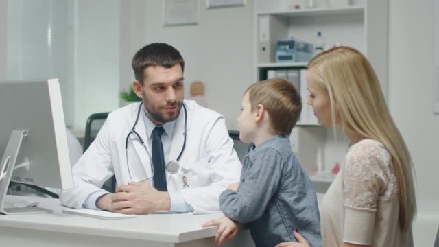At Doctor's Office. Well Natured Male Doctor Talks and Jokes with Little Boy and His Mother. In Slow Motion. Shot on RED Cinema Camera in 4K (UHD).