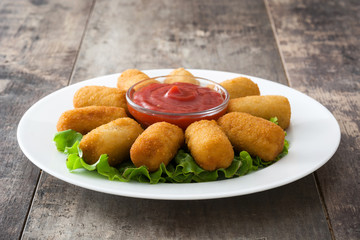 Traditional fried Spanish croquetas (croquettes) with ketchup in plate on wooden background
