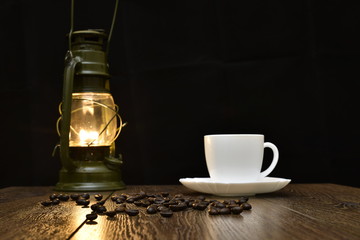 Cup of hot coffee, scattered grains and lamp - blured