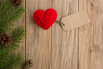 The branch of a Christmas tree and heart on a wooden table. Love