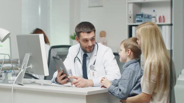 Male Doctor Consults Young Boy and His Mother with a Help of a Tablet.  Shot on RED Cinema Camera in 4K (UHD).