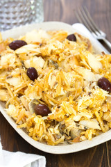 codfish with potato chips and olives on white plate