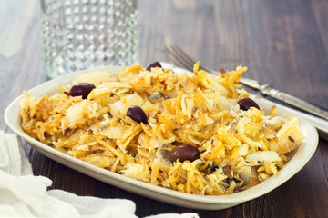 codfish with potato chips and olives on white plate
