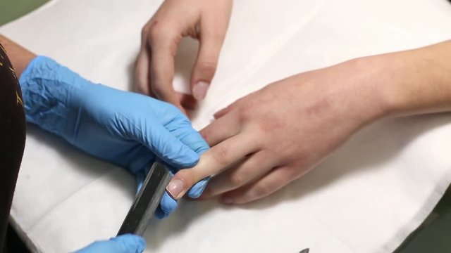 manicurist makes the manicure for young caucasian woman in beauty salon. hands close up