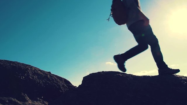 Man jumping over a gap in slow motion high up on a mountain hike