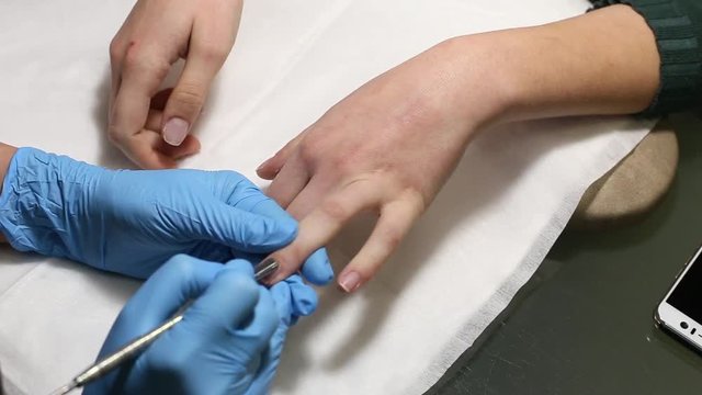 manicurist makes the manicure for young caucasian woman in beauty salon. hands close up