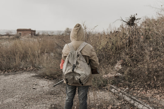 wandering boy. boy with a gun. boy goes to an abandoned building. boy stands in front of a building. Post apocalypse. Boy traveling on foot in a post-apocalyptic world in search of food. 