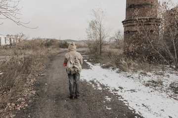 wandering boy. boy with a gun. boy goes to an abandoned building. boy stands in front of a building. Post apocalypse. Boy traveling on foot in a post-apocalyptic world in search of food. 