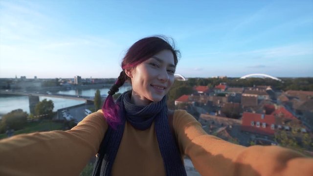 Woman tourist taking selfie on phone in fron of a city