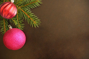 Christmas tree branch with purple and red wavy ball on a dark background. Top view.