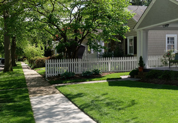 Residential city block in spring. Homes, sidewalk, green lawn.