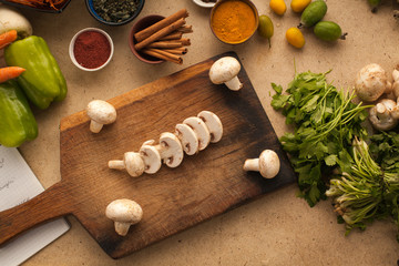 Sliced mushrooms on wooden table with vegetables for cooking. He