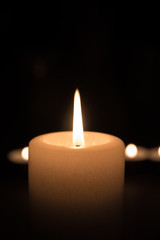 Kerze brennt vor schwarzem Hintergrund