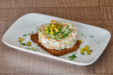 Traditional New Year's salad. Russian traditional salad olivier with pea in the plate.