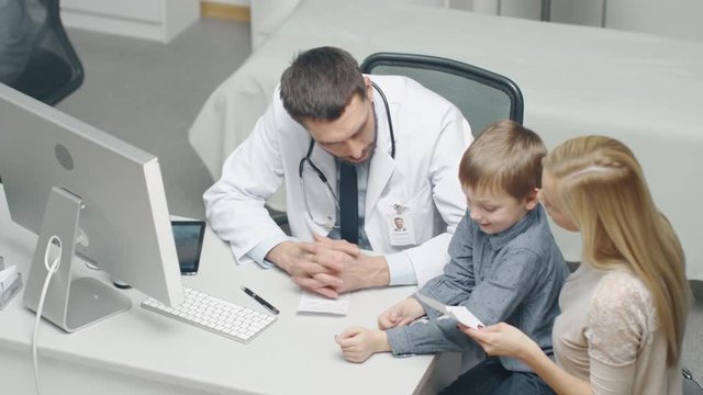 Male Doctor Writes a Prescription to a Young Boy and His Motherand. Gives Prescriptionto Mother with Some Oral Recommendations. Shot on RED Cinema Camera in 4K (UHD).