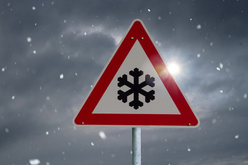Verkehrsschild warnt vor Straßenglätte durch Schneefall