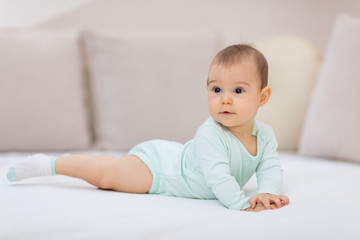 Baby girl on white bed / Cute baby girl lying on her tummy