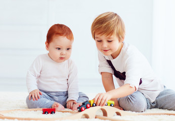cute kids playing with toy railway road at home