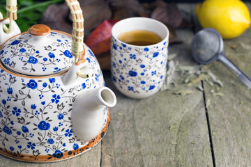 Autumn cup of tea with teapot on a rustic table.