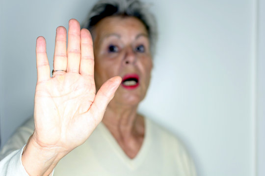 senior woman with her hands signaling to stop over light background 