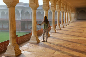 Fototapeta premium Young woman standing in colonnade walkway leading to Diwan-i- Kh