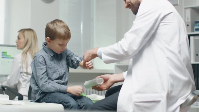 Male Doctor Removes Plaster from a Boy's Healed Hand. Boy is Very Happy.  Shot on RED Cinema Camera in 4K (UHD).