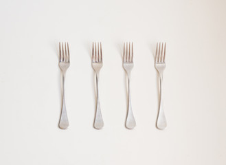 Food background - high angle view of four forks in a row on a white table